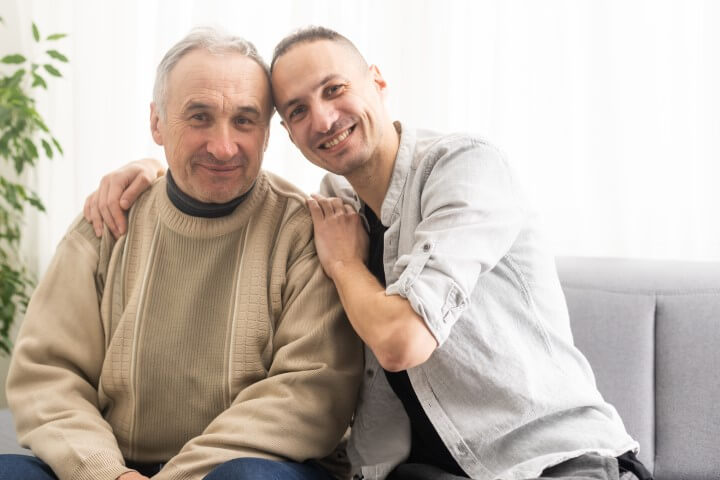 older man on couch next to son