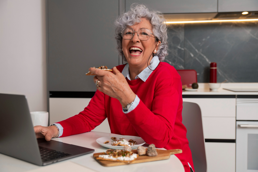 Happy elderly woman eating her lunch at home